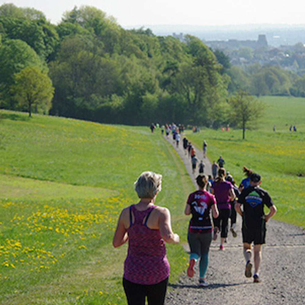 Photograph of runners at Aston Court Parkrun on a path with greenery and trees in the background