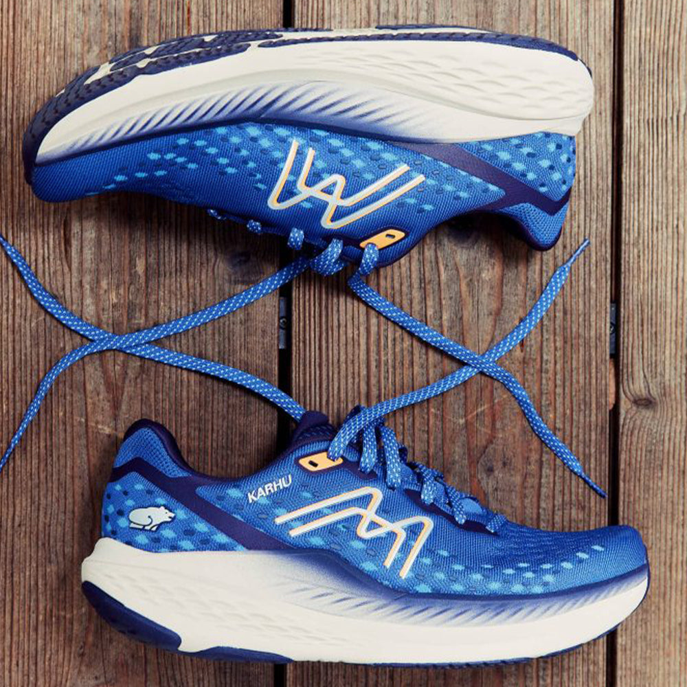 Photograph of a pair of blue Karhu running shoes ling on a wooden surface