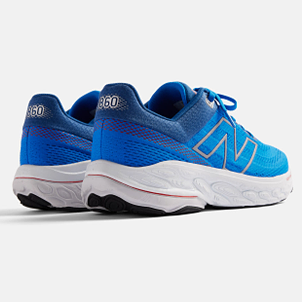 Photograph of a pair of blue New Balance 860 trainers against a white background