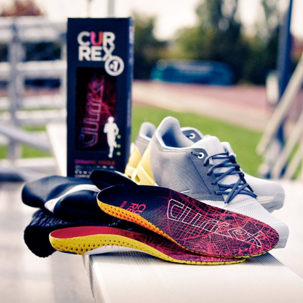 Image of some Currex insoles and packaging alongside a pair of running shoes on a table outside