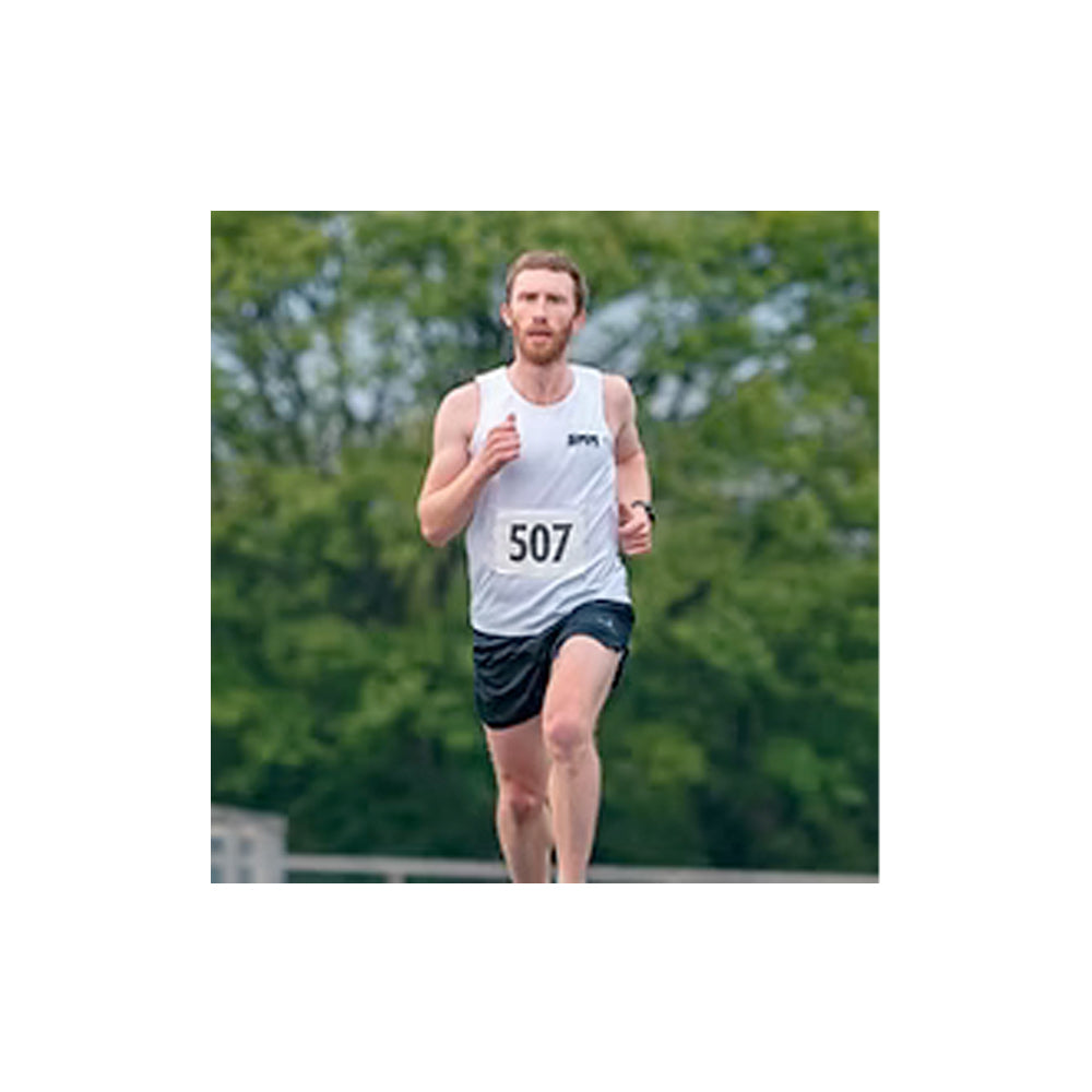 Man running with a number 507 on his shirt against a green blurred background