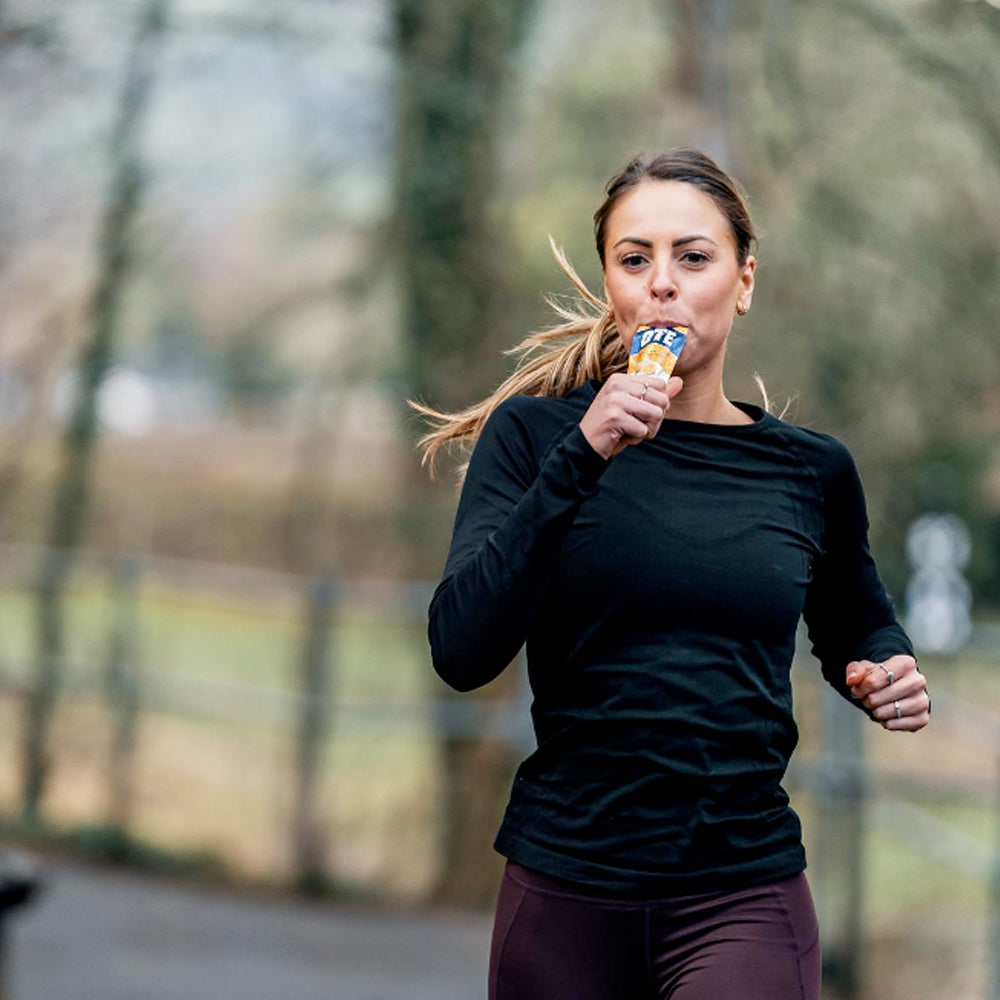 Image of a woman running outside whilst taking an energy gel