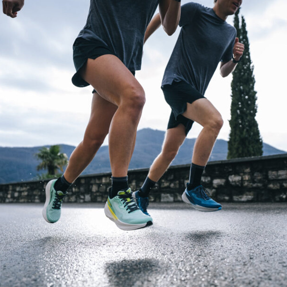 Photograph of two men running on tarmac outside wearing shorts and Altra running shoes