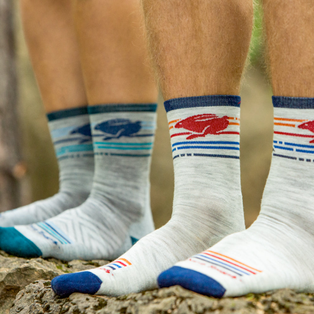 Image of two pairs of feet wearing running socks and bare legs on a mixed terrain surface outside