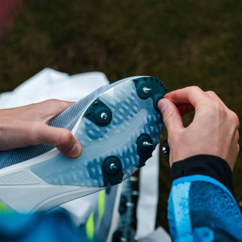 Image of a hand checking spikes to the bottom of a running shoe
